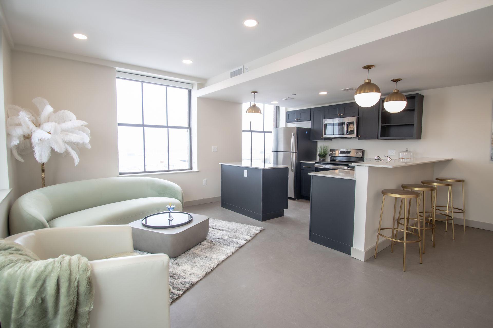 A living room with a couch , chairs , and a kitchen.