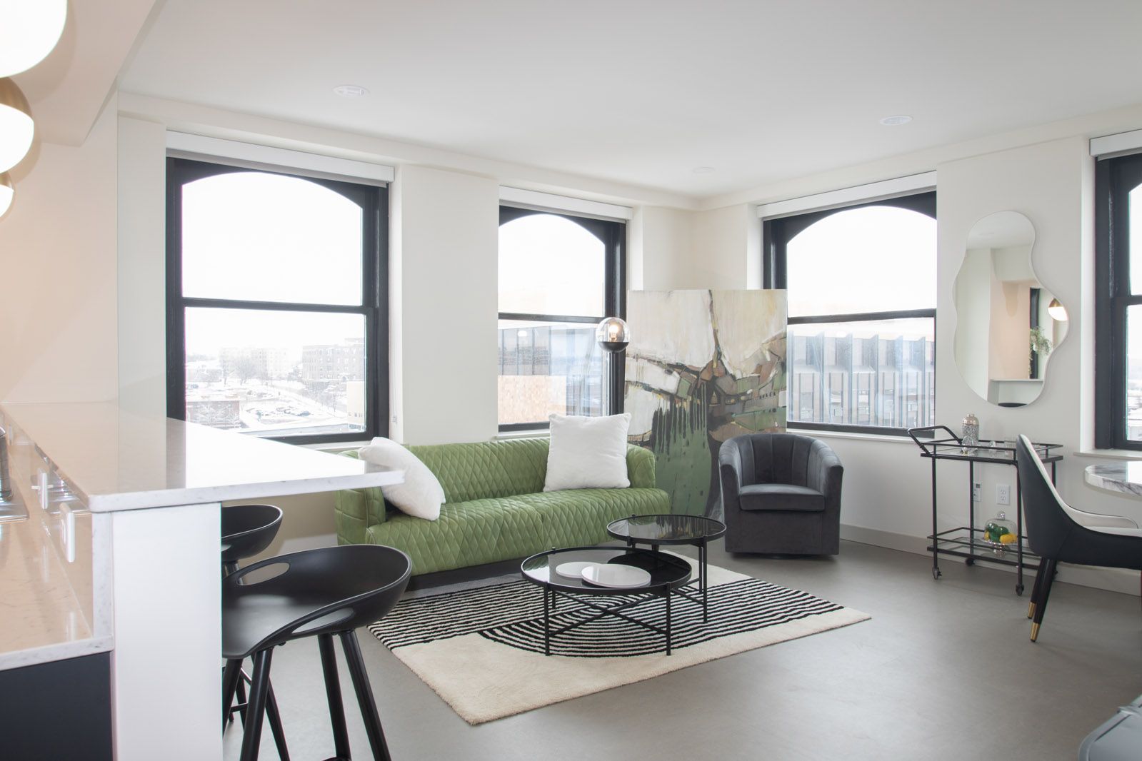 A living room with a green couch and black chairs