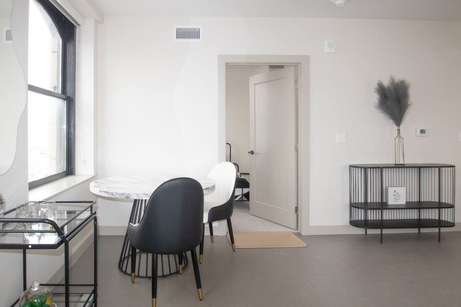 A living room with a table and chairs and a window.