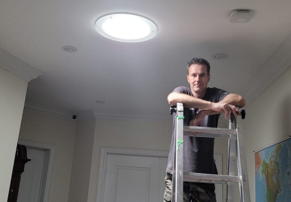 A man in a white shirt is working on a ceiling