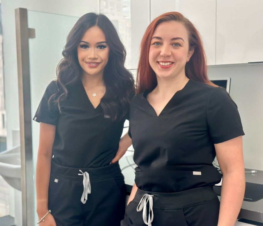 Two women in black scrubs are posing for a picture