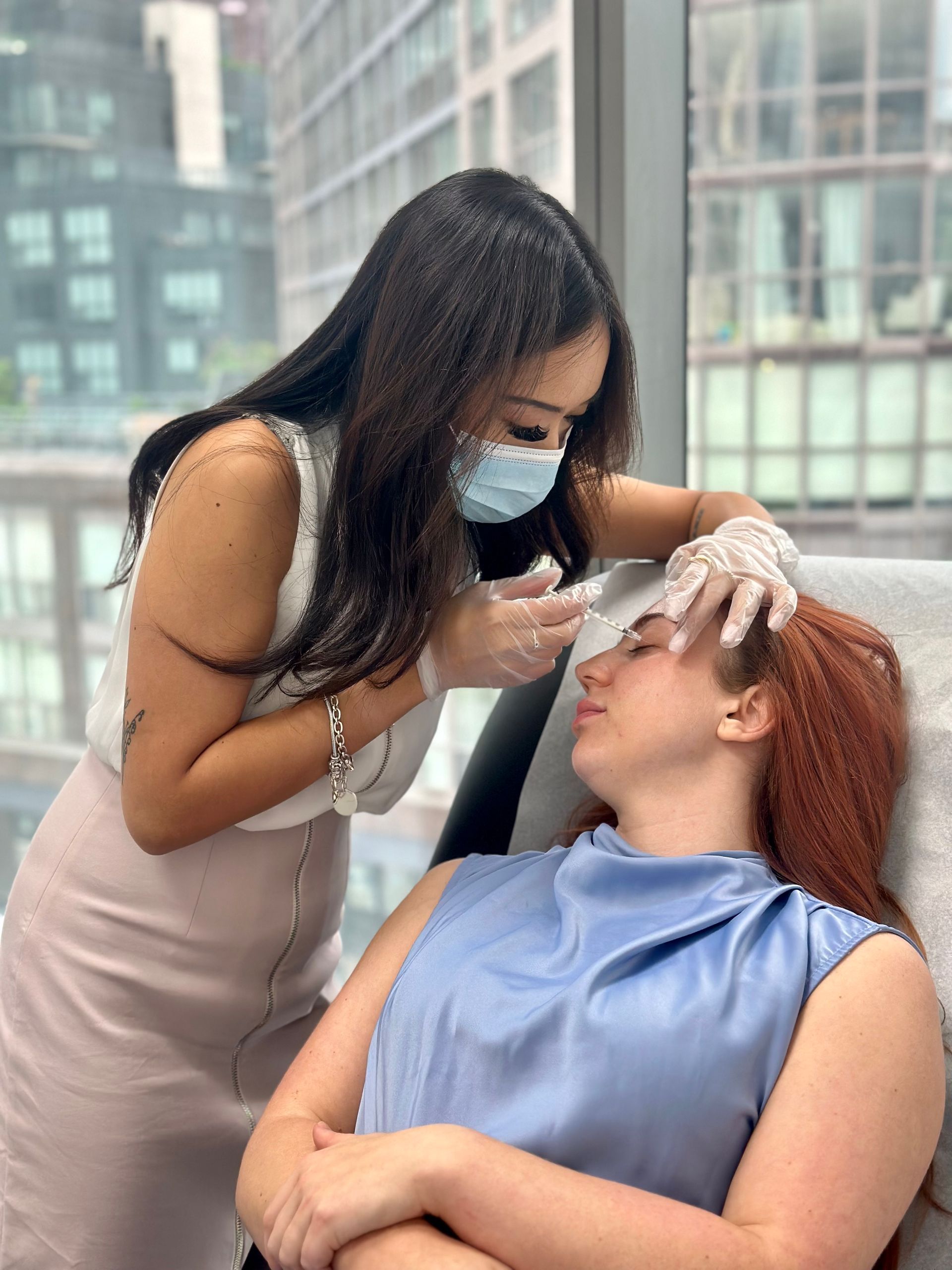 A woman is getting a botox injection in her forehead.