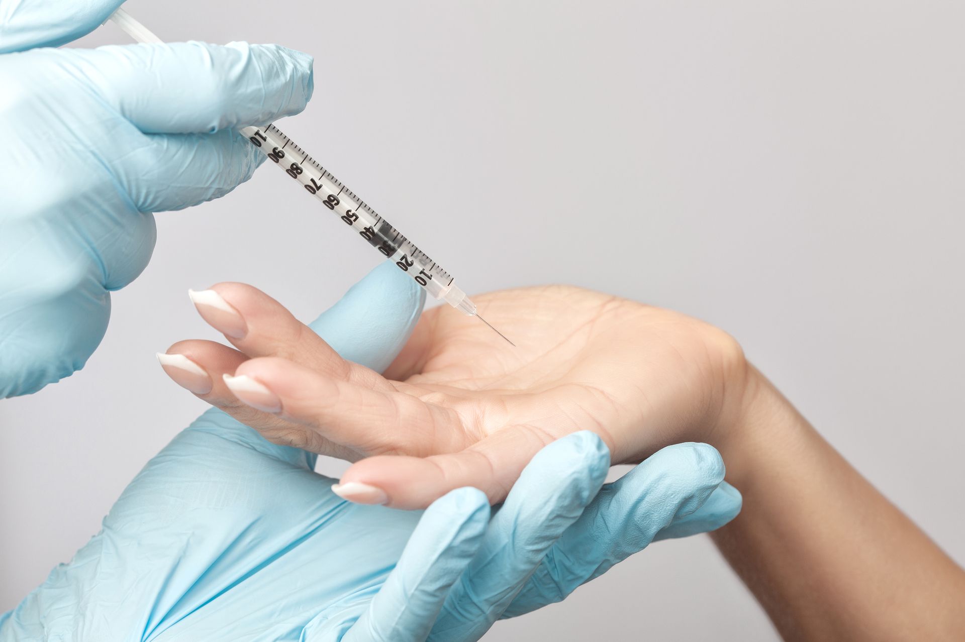 A woman is getting an injection in her hand.