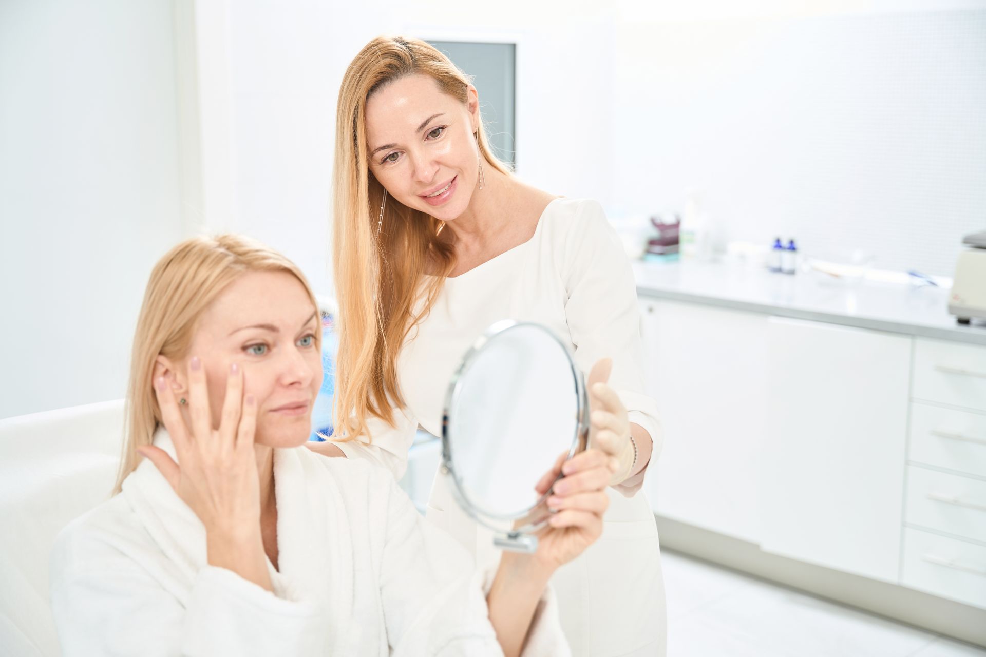 A woman is looking at her face in a mirror.