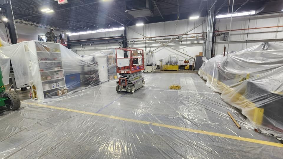 A forklift is driving through a large warehouse covered in plastic.