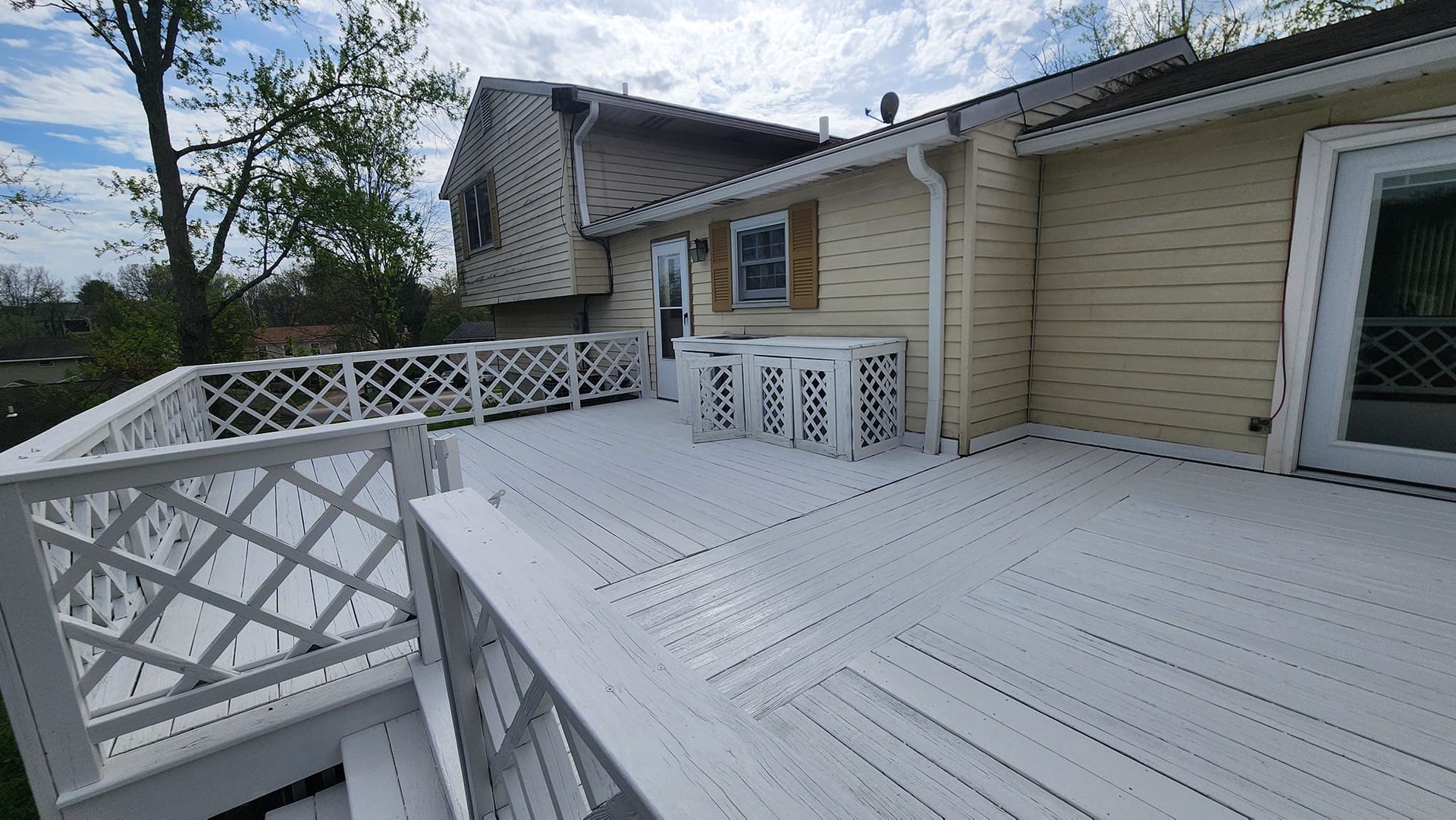 A white deck with a white railing is in front of a house.