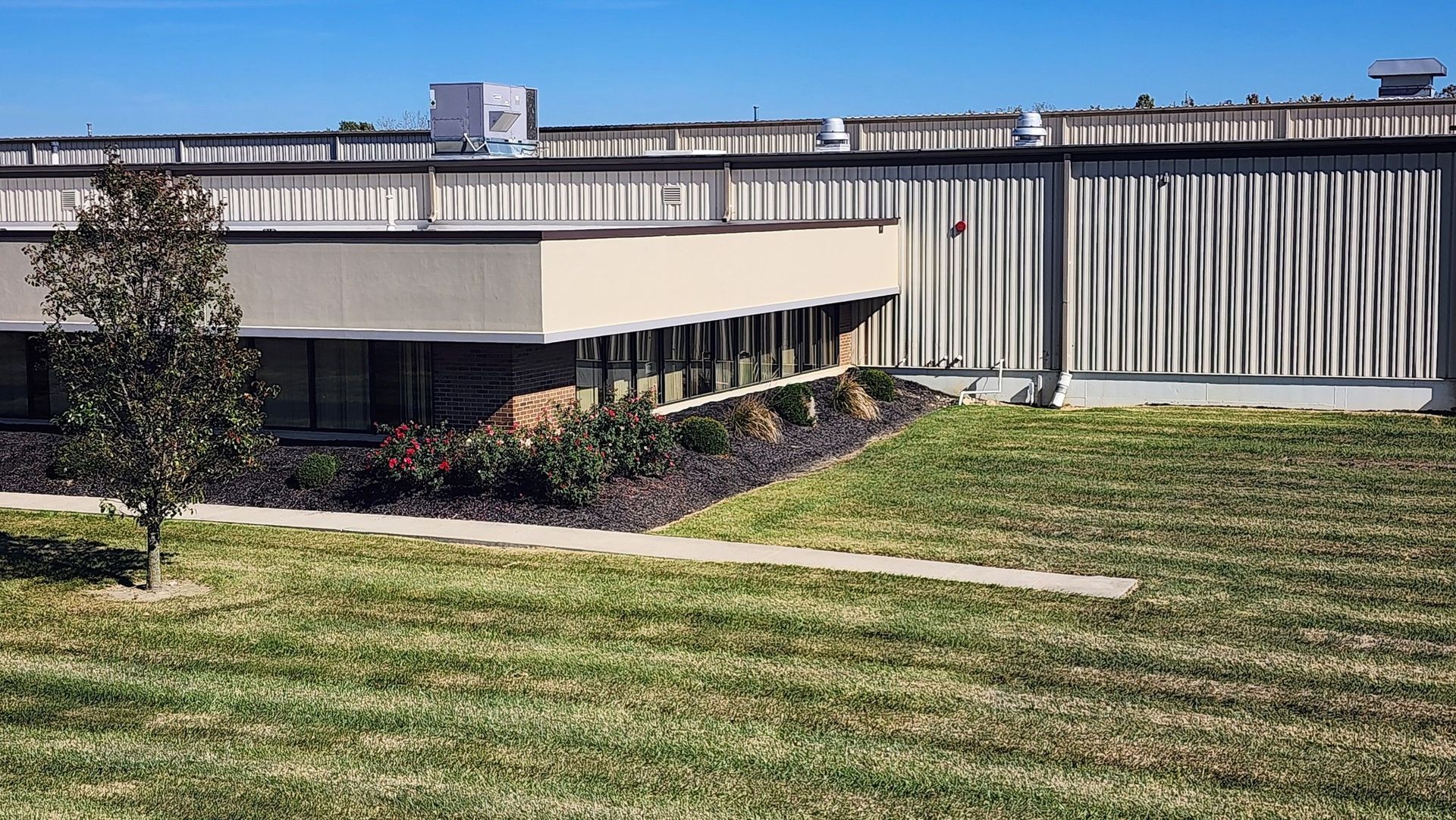 A large building with a lot of windows is surrounded by a lush green field.