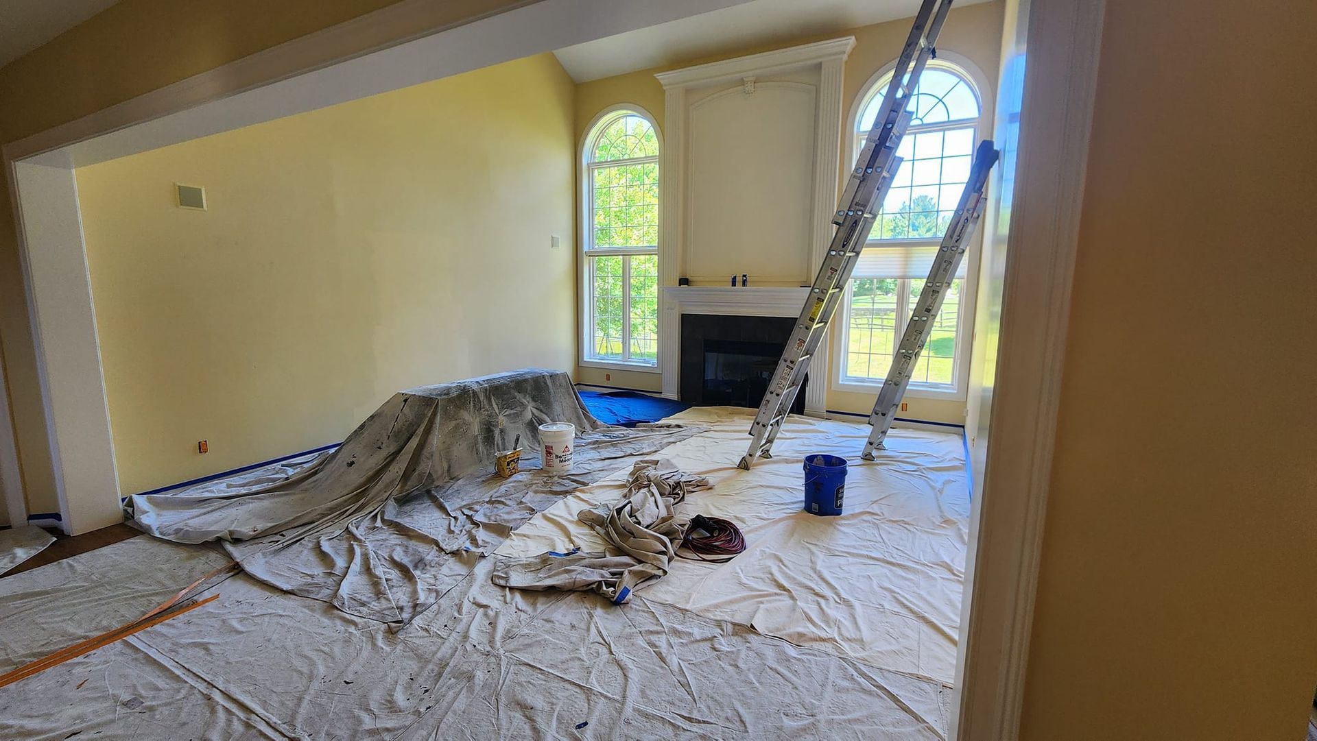 A living room is being painted with a ladder in the background.