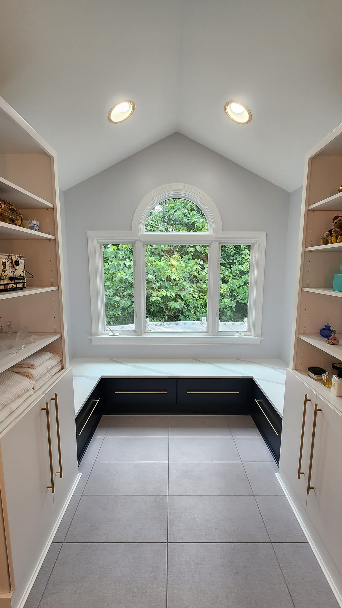 A room with a lot of shelves and a window.