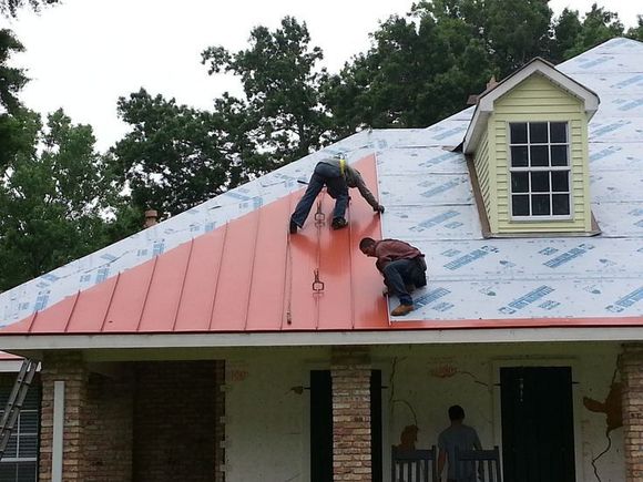 Two men are working on the roof of a house