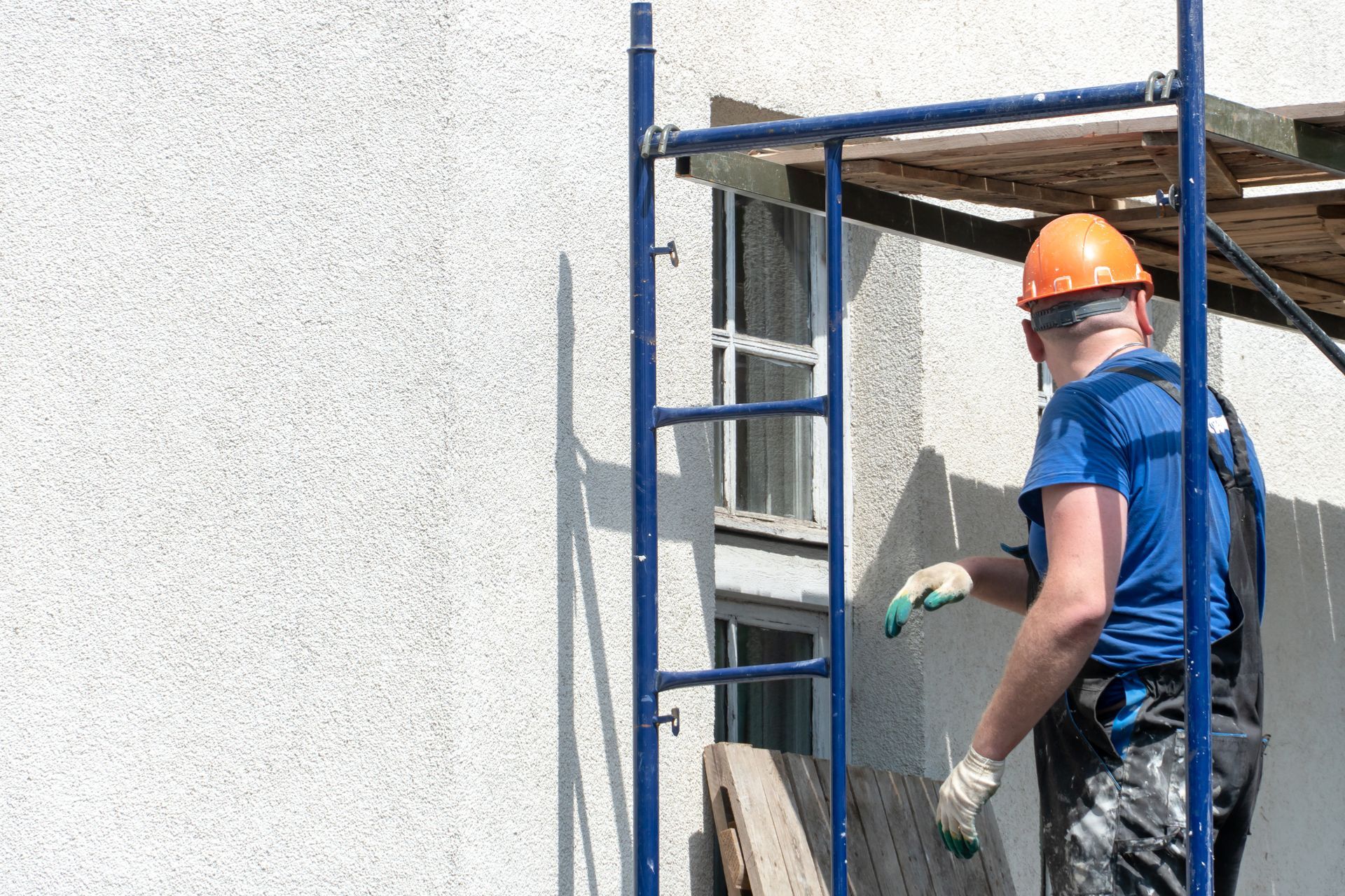 Construction worker in an orange helmet working on scaffolding.