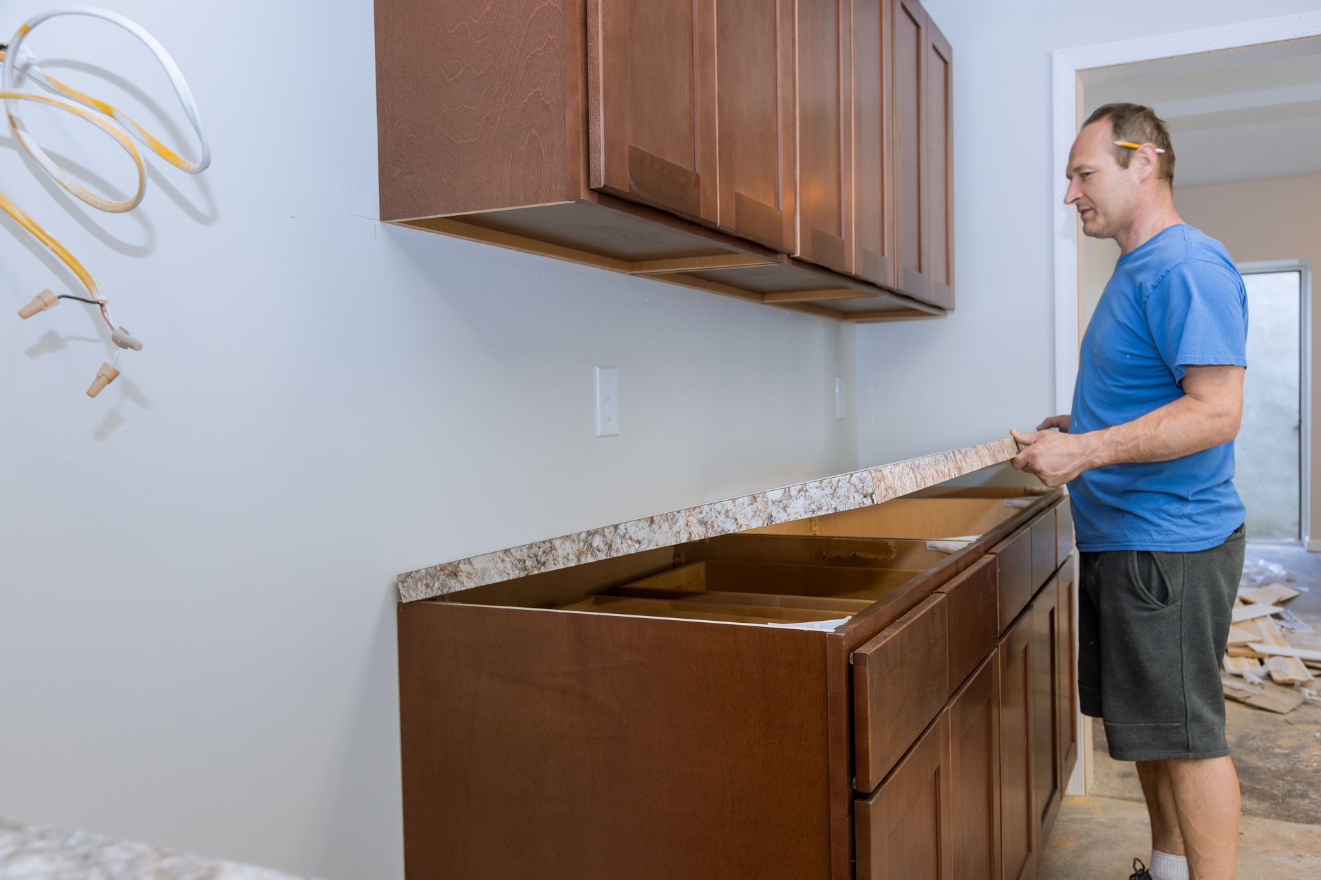 A man installs a new laminate countertop during a kitchen remodel.