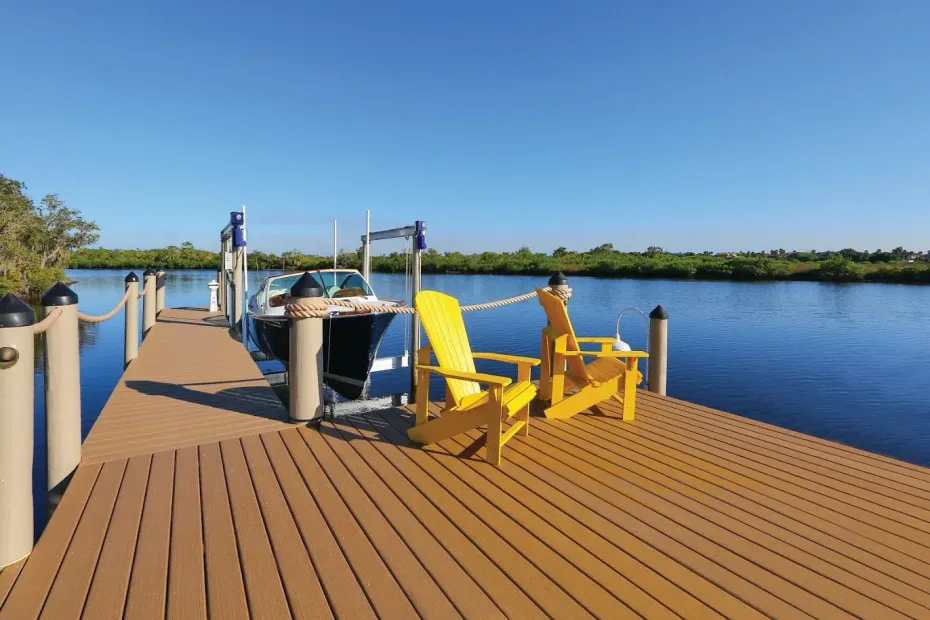 Two yellow chairs are sitting on a dock next to a boat.