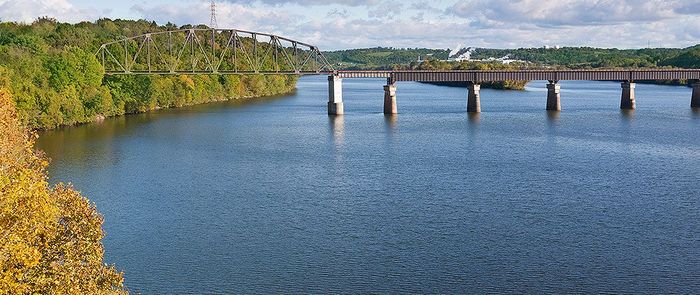 A bridge over a large body of water surrounded by trees.