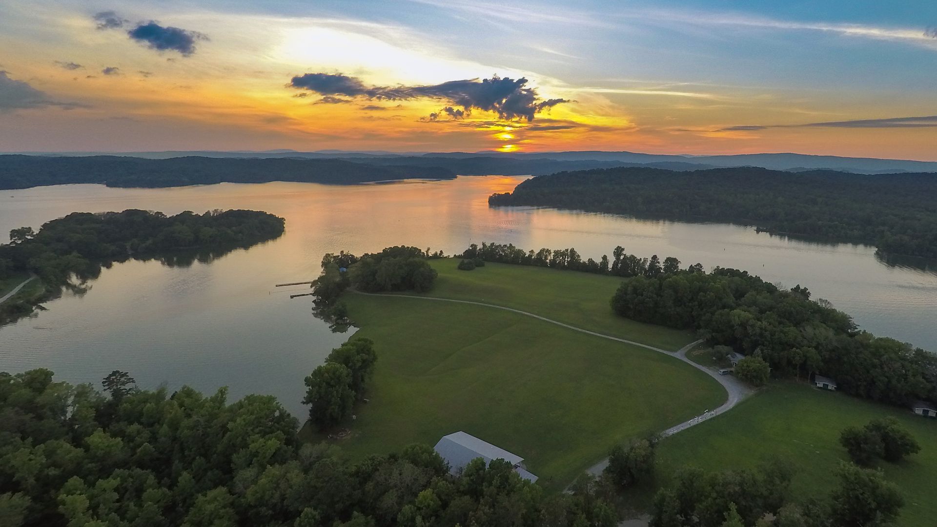 An aerial view of a lake at sunset with a small island in the middle.