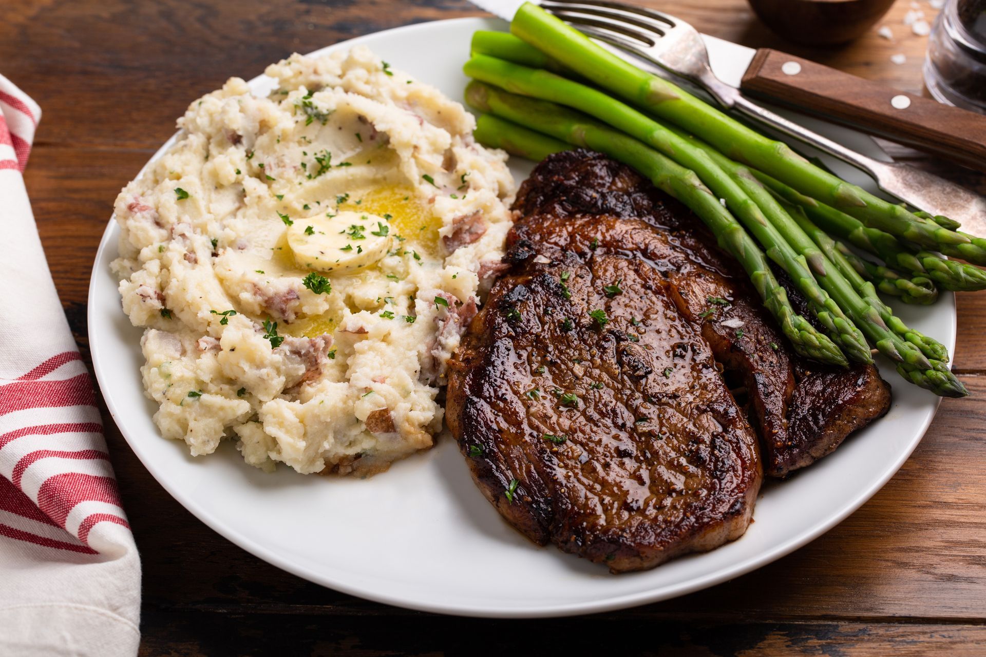 Plate of steak, mashed potatoes with butter, and asparagus.