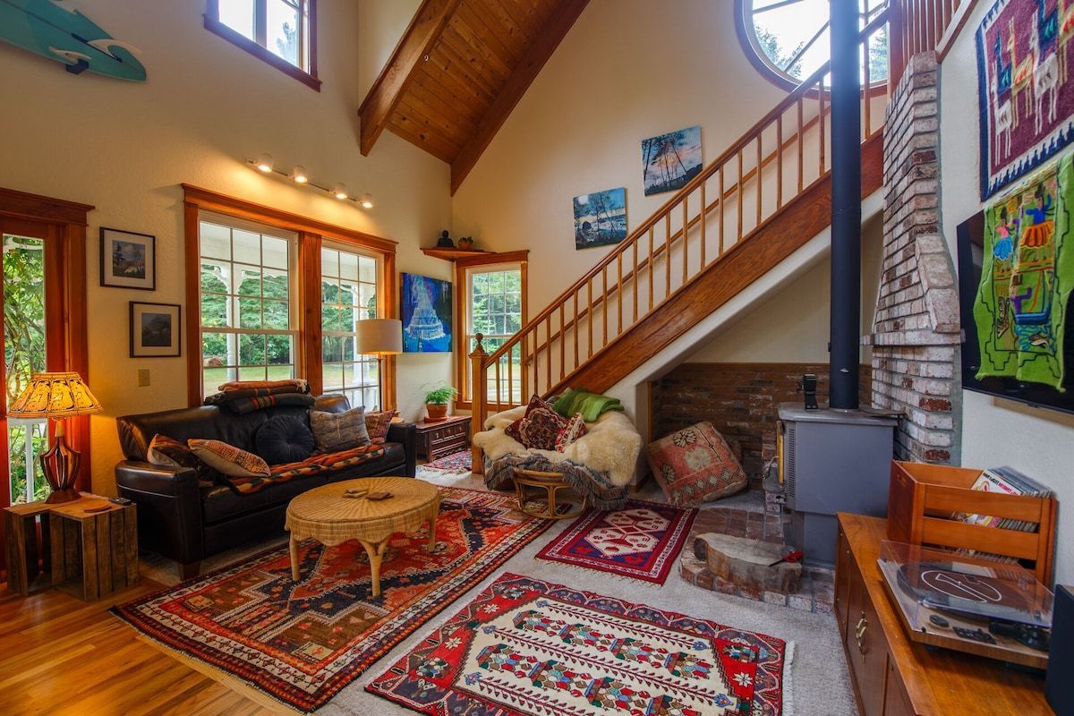 Cozy living room with wood floors, area rugs, leather sofa, fireplace, and staircase.