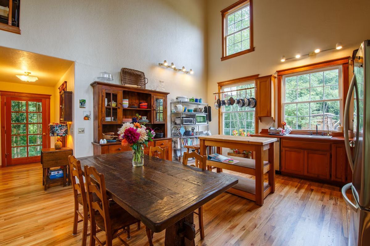 Spacious kitchen with wood cabinets, island, and dining table; windows and natural light.