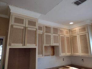 A kitchen under construction with wooden cabinets and a ceiling fan.