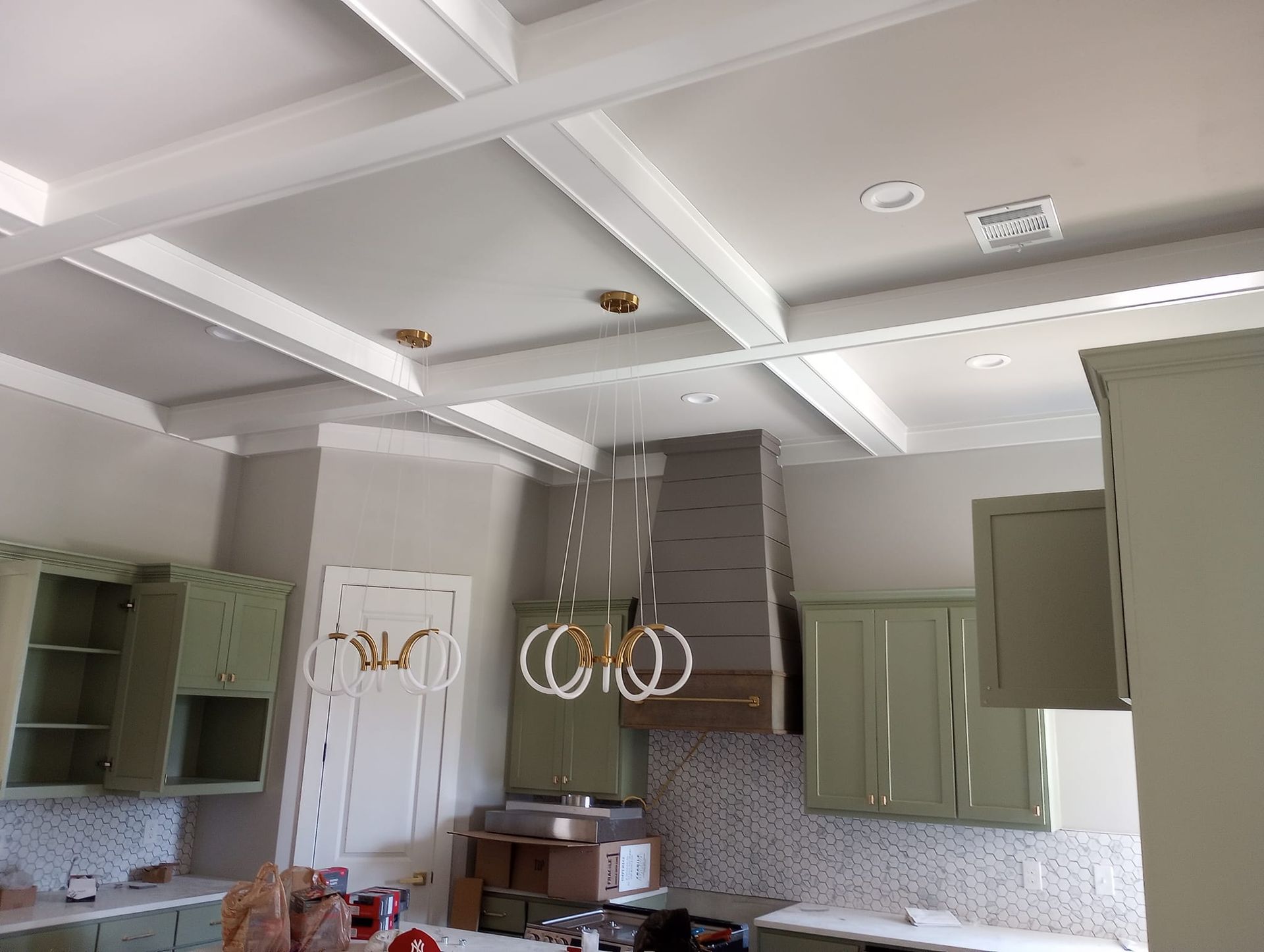 A kitchen with green cabinets and a coffered ceiling.
