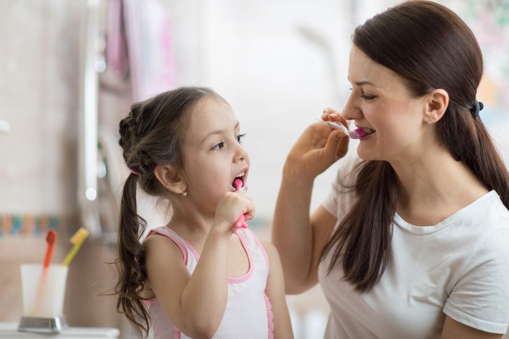 Mother Teaching Kid Daughter Teeth Brushing in Bathroom — Dental Clinic in Buderim, QLD