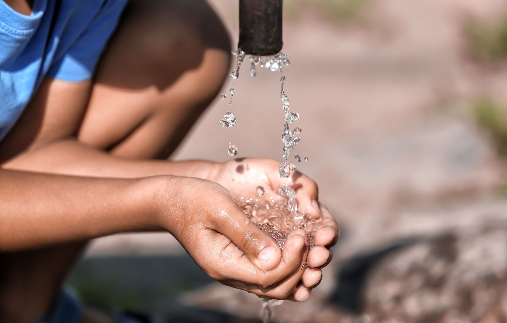 A child is washing their hands under a faucet