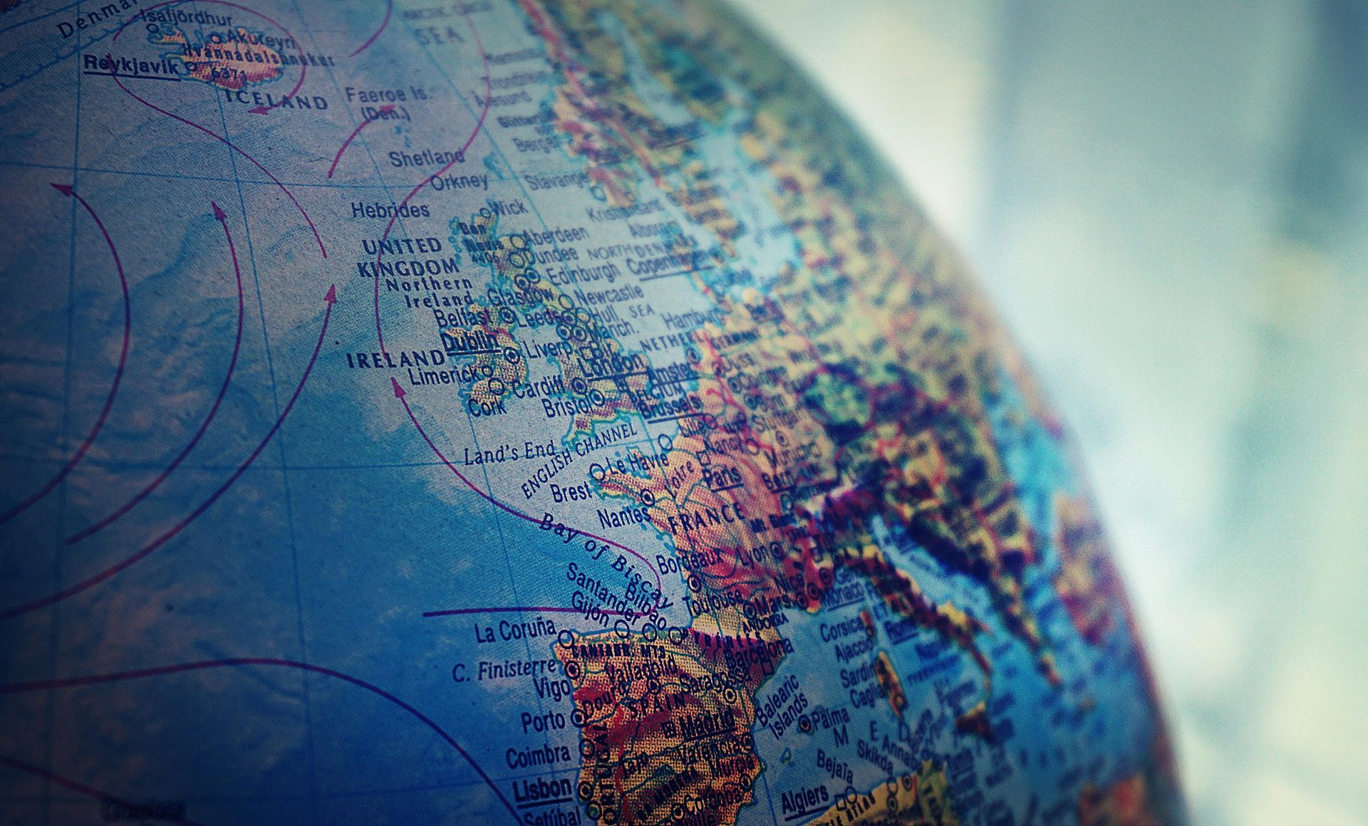 Close-up of a globe, primarily showing North America and surrounding ocean. Blue, brown, and white colors dominate.
