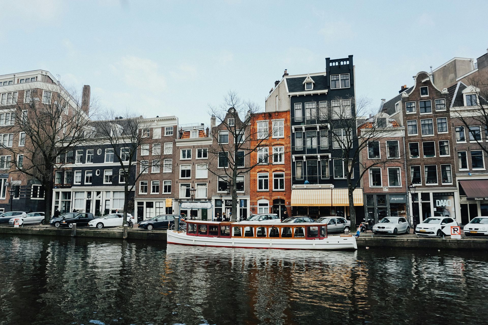 A boat is floating on a river in front of a row of buildings.