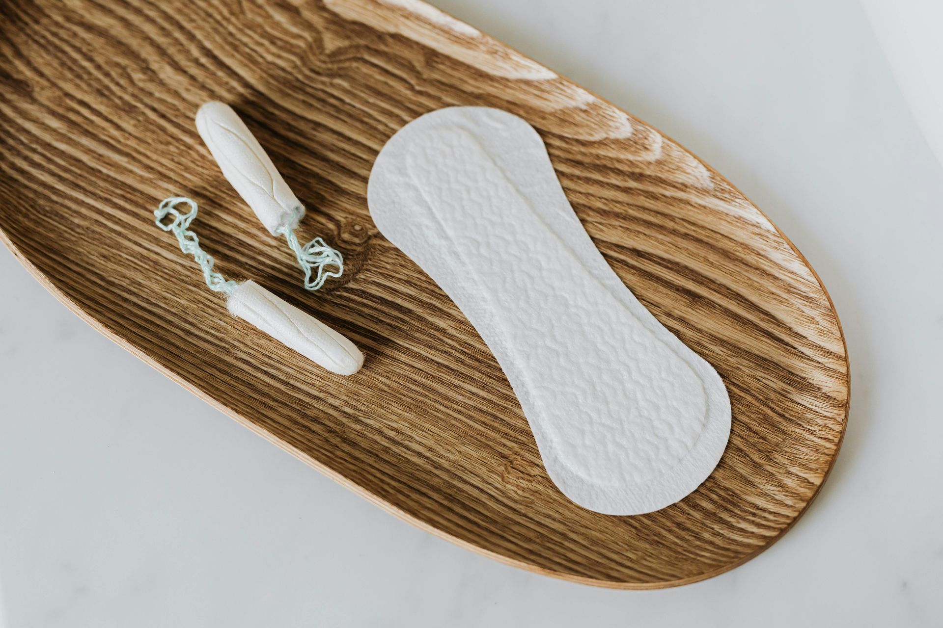 A wooden tray with a pad and two tampons on it.