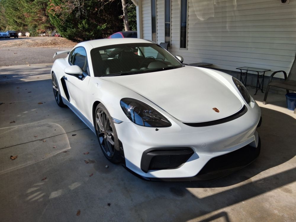 Tow truck operator shakes hands with a driver beside a car on the truck.