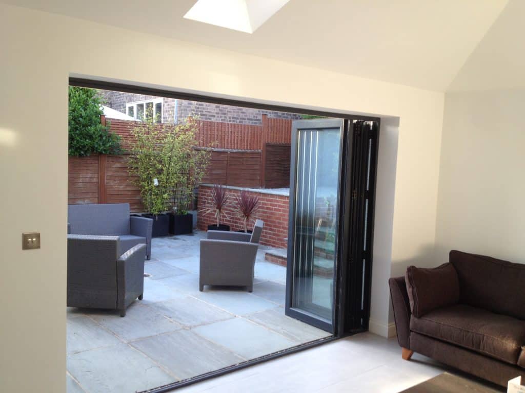 A living room with a couch and chairs open to a patio