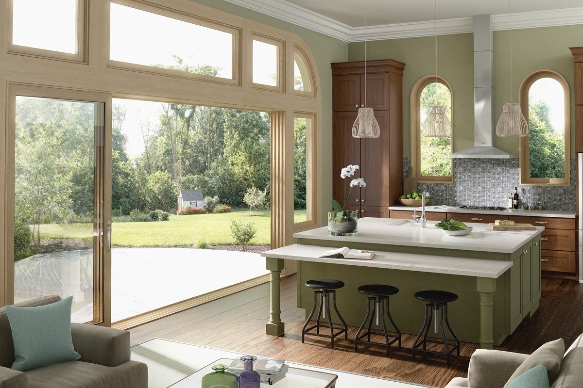 A living room with a large island in the middle and a kitchen with sliding glass doors.