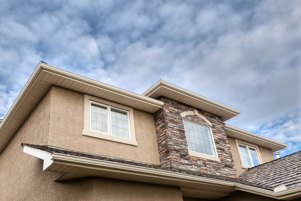 The roof of a house with a cloudy sky in the background.