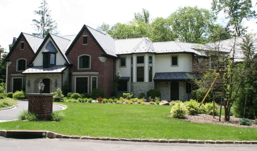 A large brick and white house with a large lawn in front of it