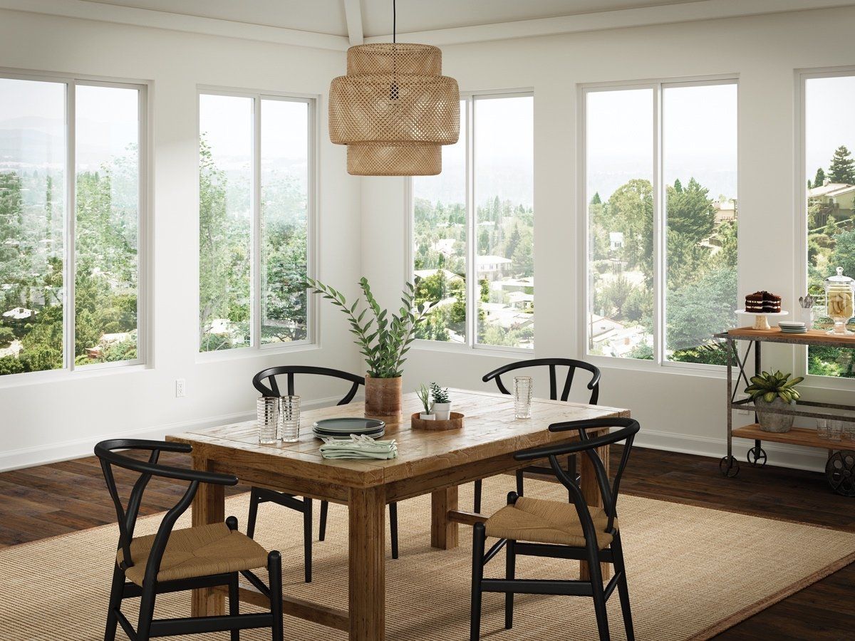A dining room with a table and chairs and lots of windows.