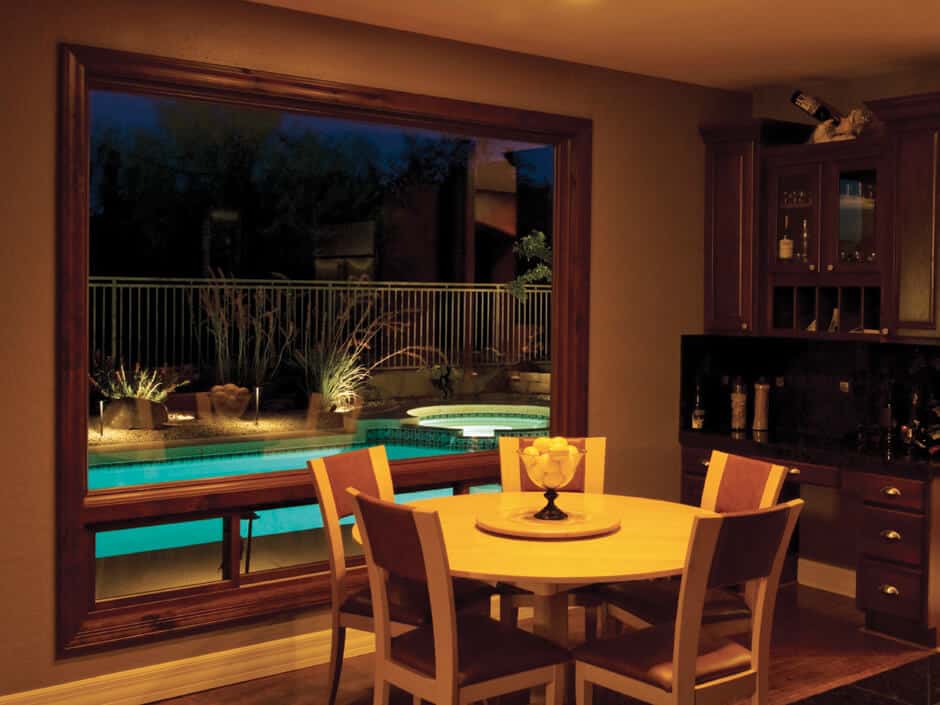 A dining room with a table and chairs and a view of a pool