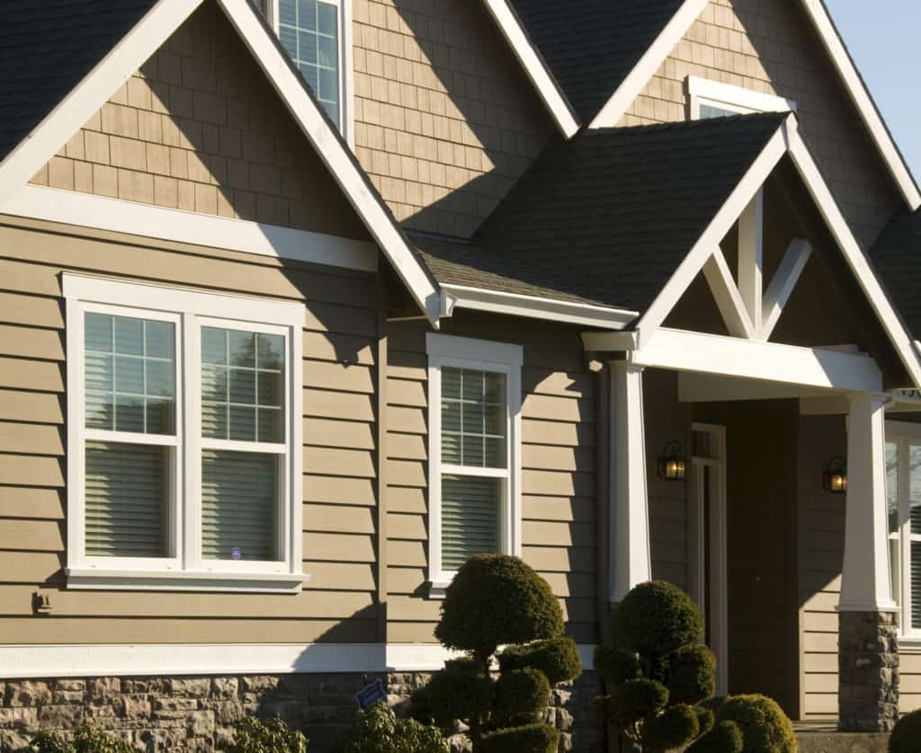 A brown house with a black roof and white trim
