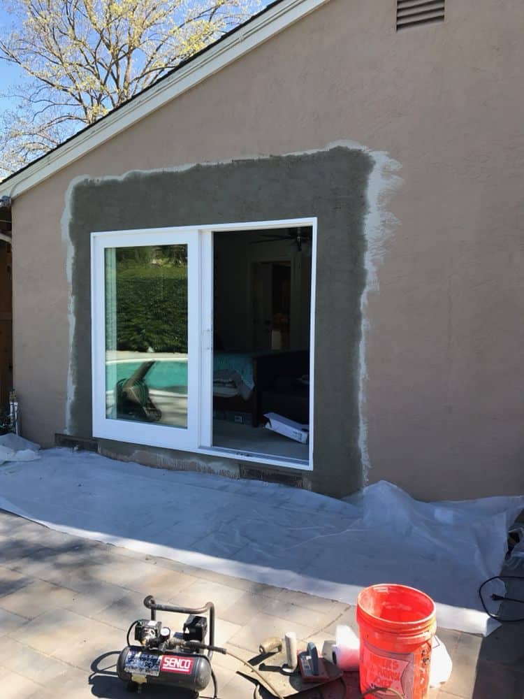 A sliding glass door is being installed on the side of a house.