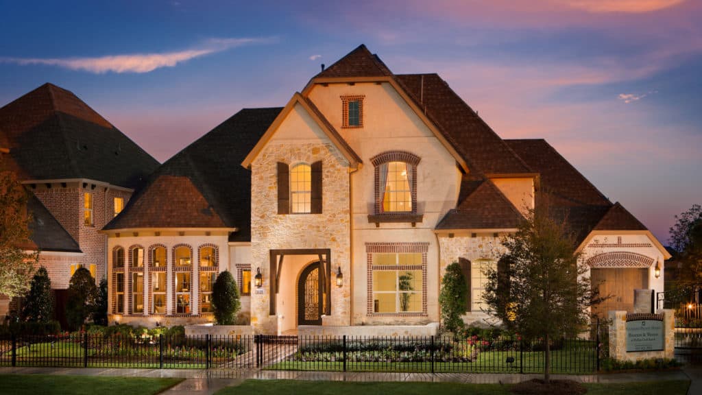 A large house with a fence in front of it is lit up at night.