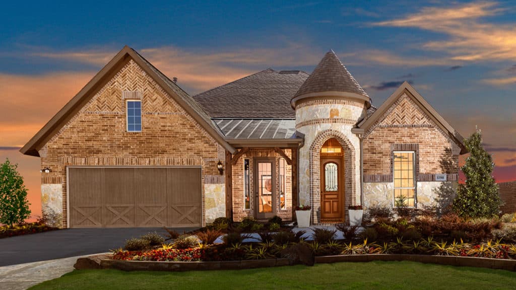 A large brick house with a castle shaped roof is sitting on top of a lush green lawn.