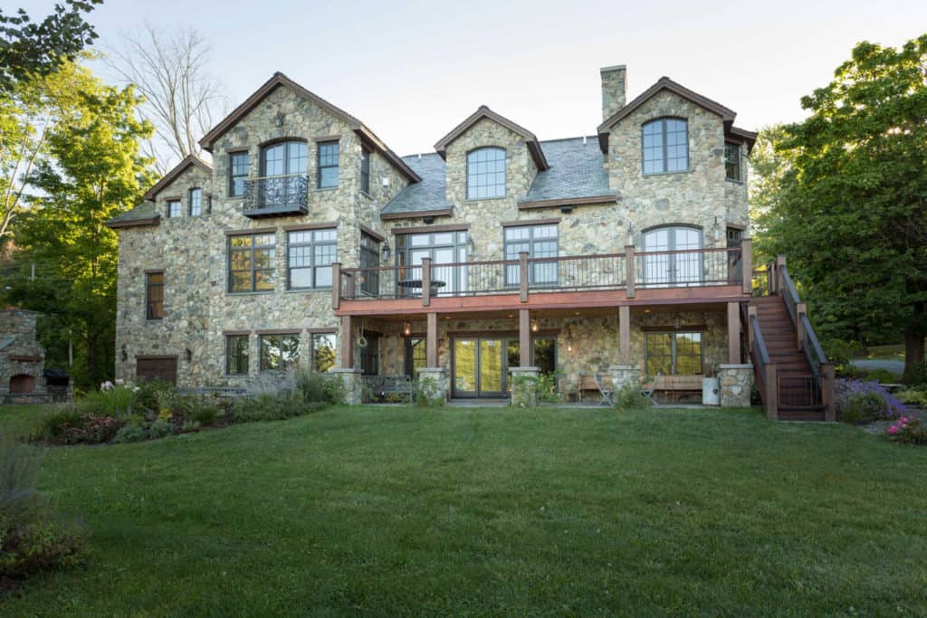 A large stone house with a large lawn in front of it.
