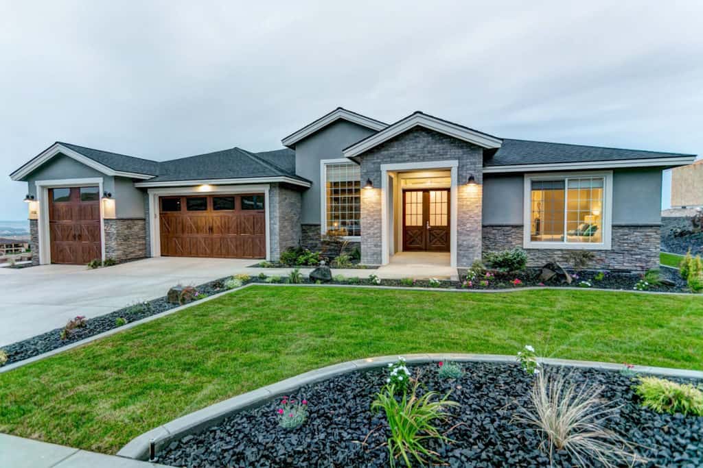 A large house with a large driveway and a large lawn in front of it.