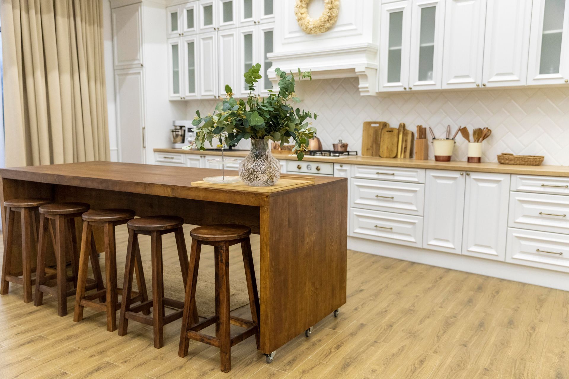 A kitchen with a long wooden table and stools.