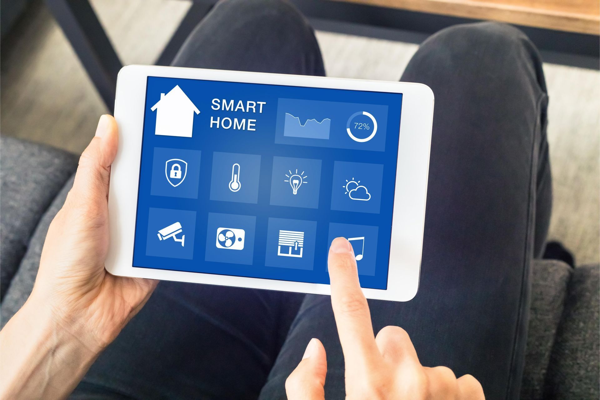 A person is holding a tablet with a smart home app on it.