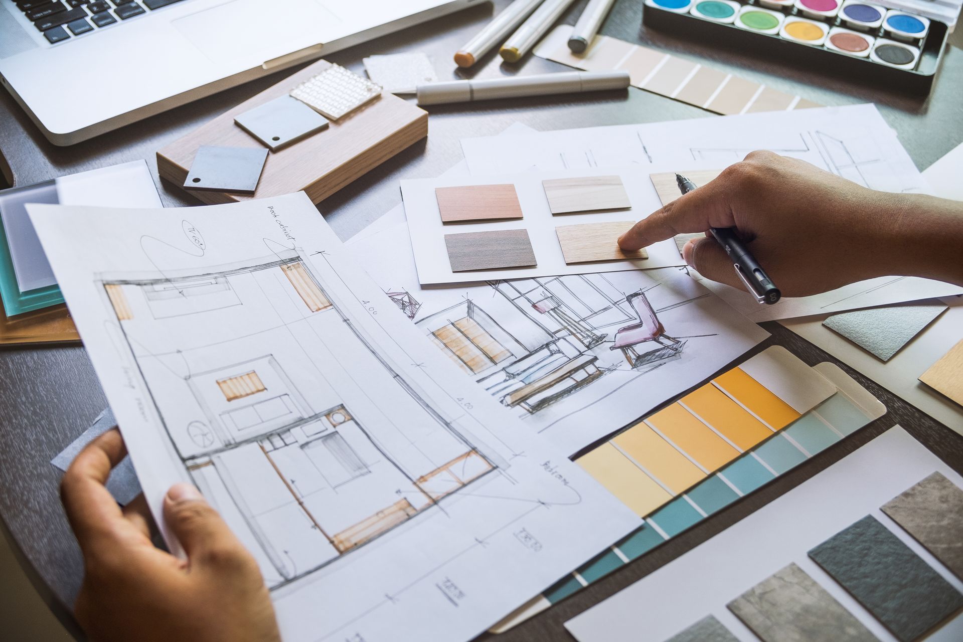 A person is drawing a floor plan of a house on a piece of paper.