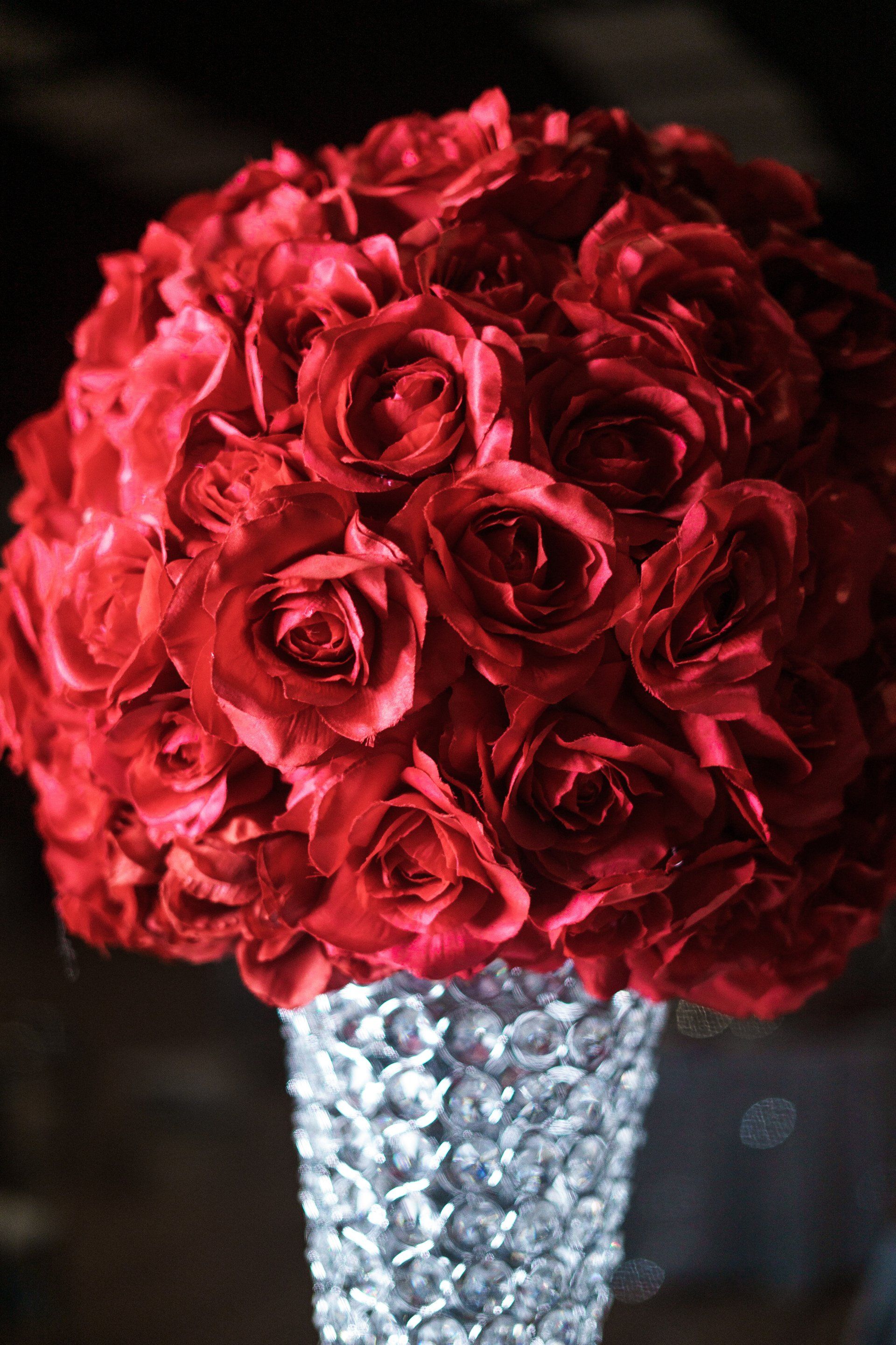 A vase filled with red roses is sitting on a table.