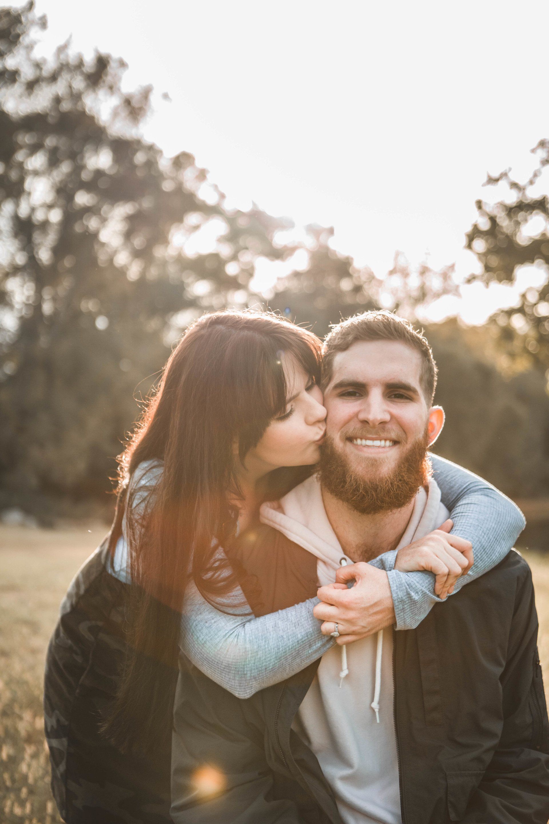 A woman is kissing a man on the cheek in a field.