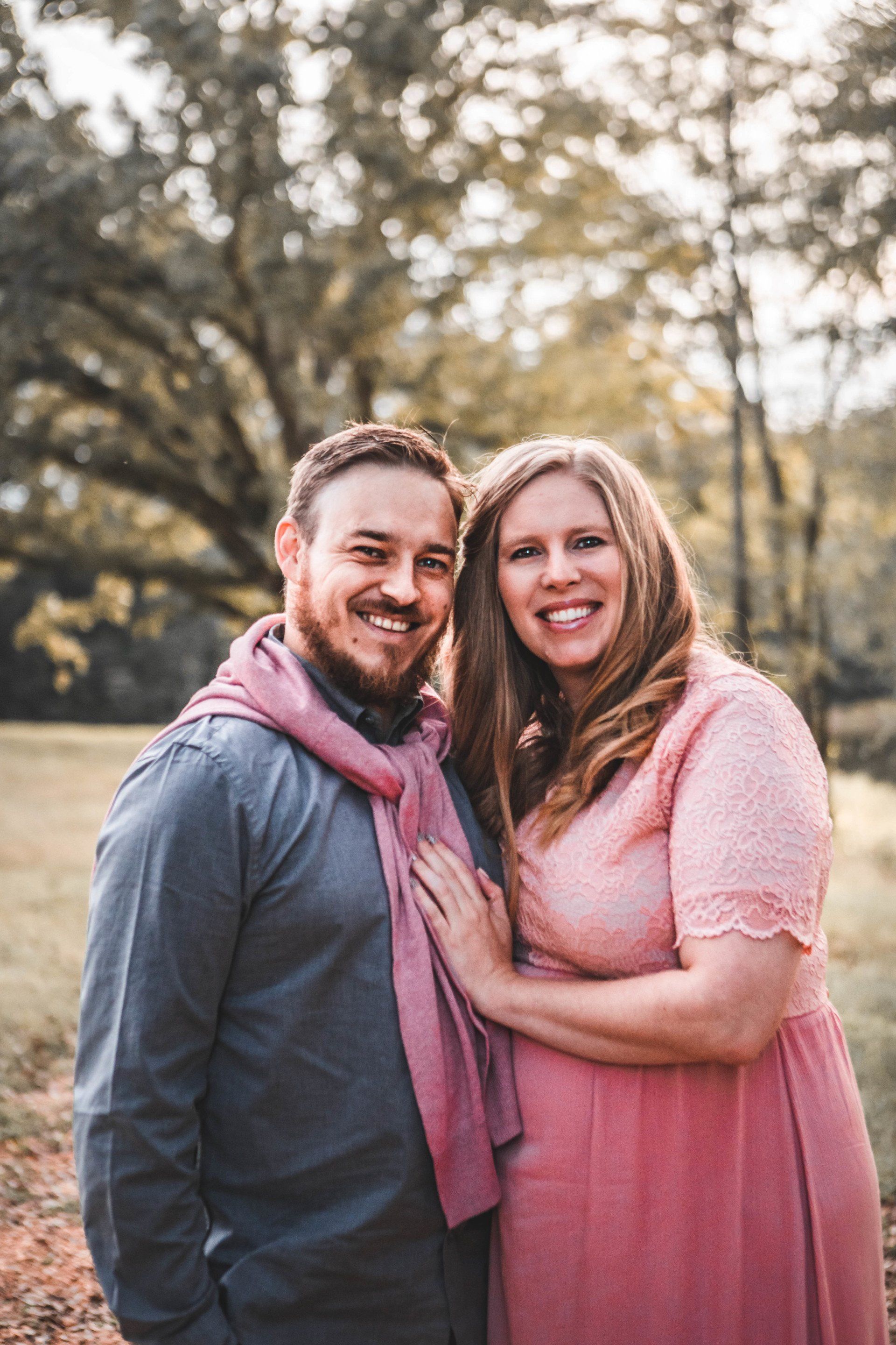 A man and a woman are posing for a picture in a field.