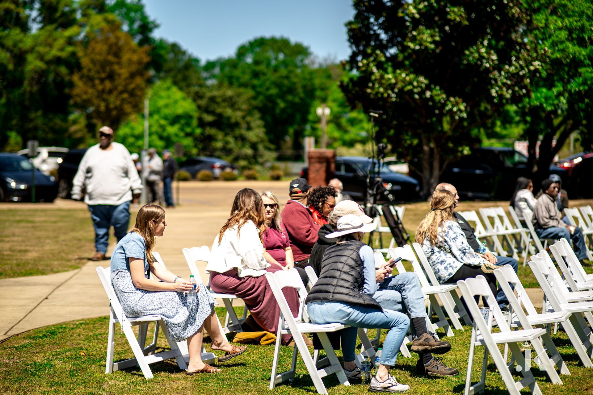 A group of people are sitting in folding chairs in a park.