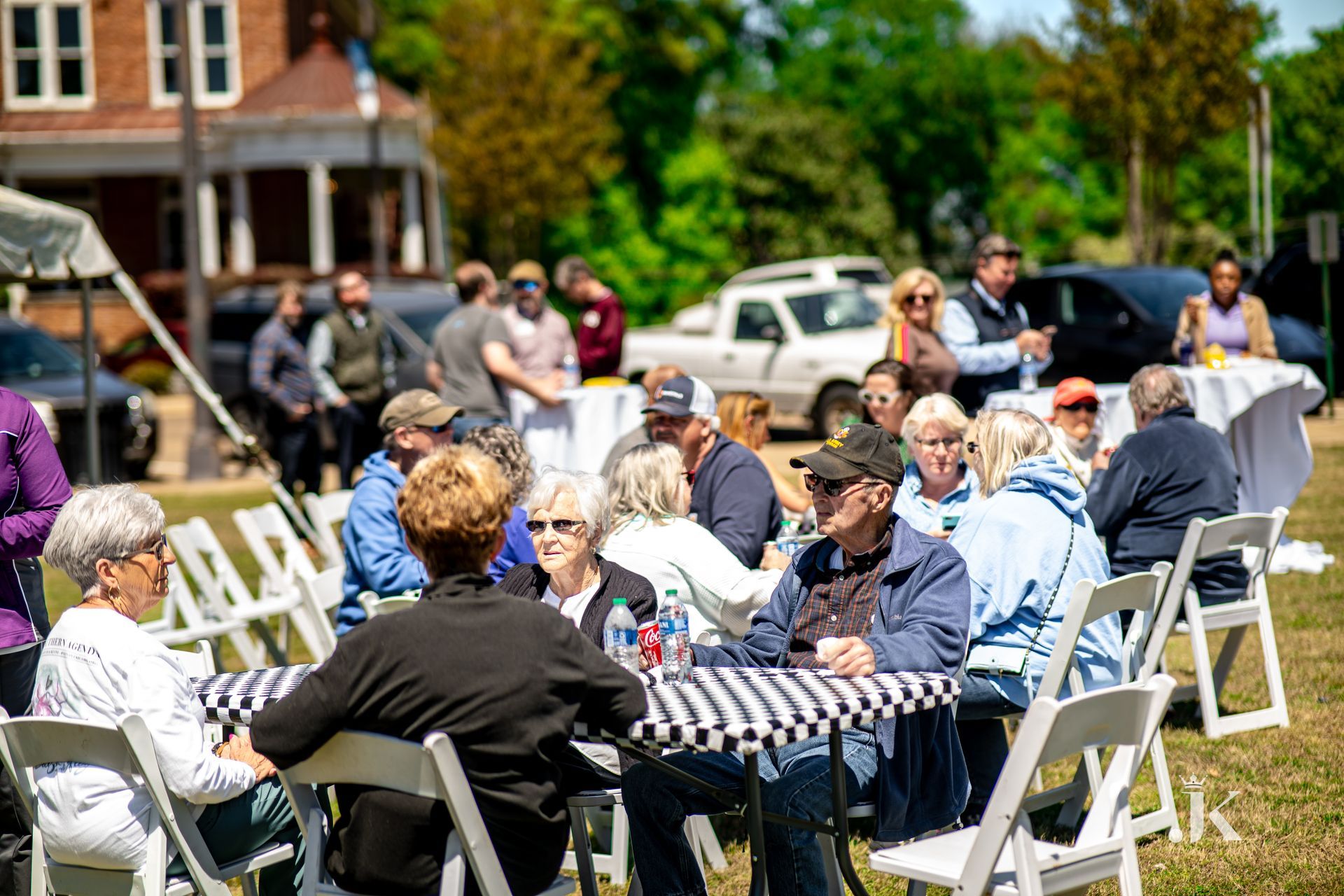 A group of people are sitting at tables in a field.